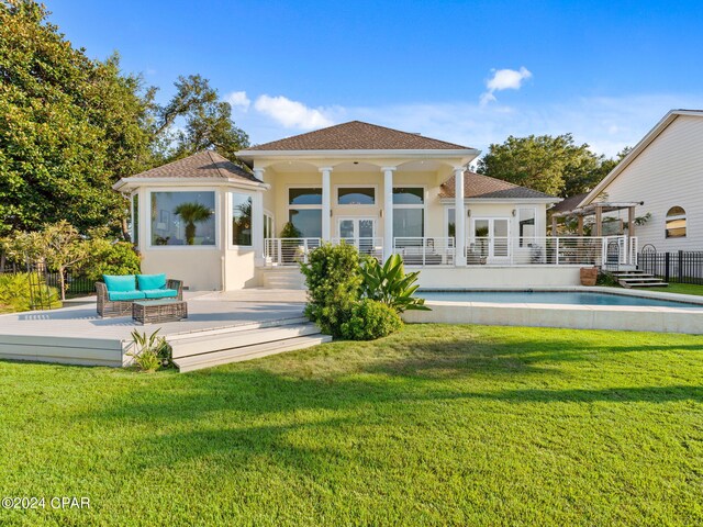 rear view of house featuring a lawn and a fenced in pool