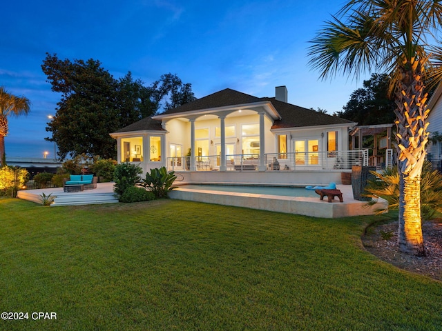 back of house featuring french doors, a lawn, stucco siding, a chimney, and a patio area