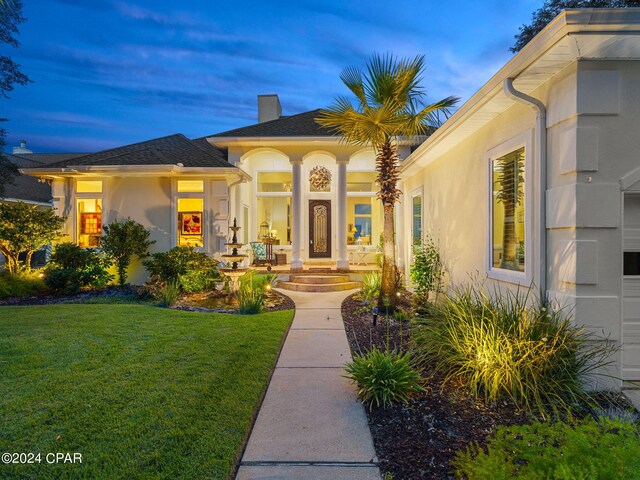 exterior entry at dusk featuring a lawn