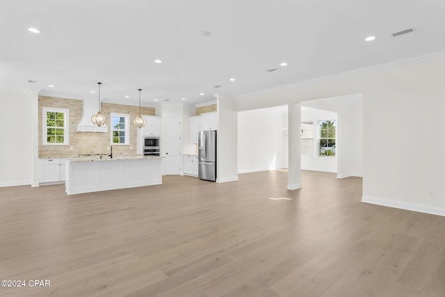 unfurnished living room featuring light hardwood / wood-style flooring, crown molding, and sink