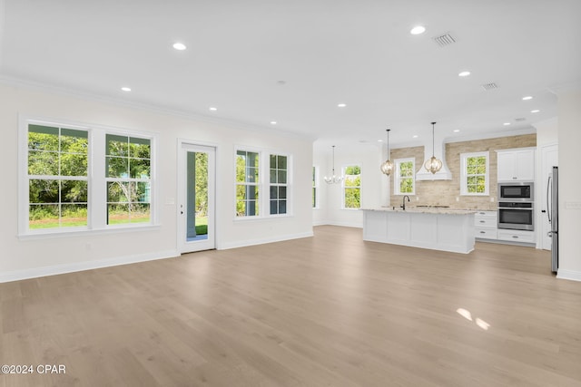 unfurnished living room with light wood-type flooring, ornamental molding, and sink