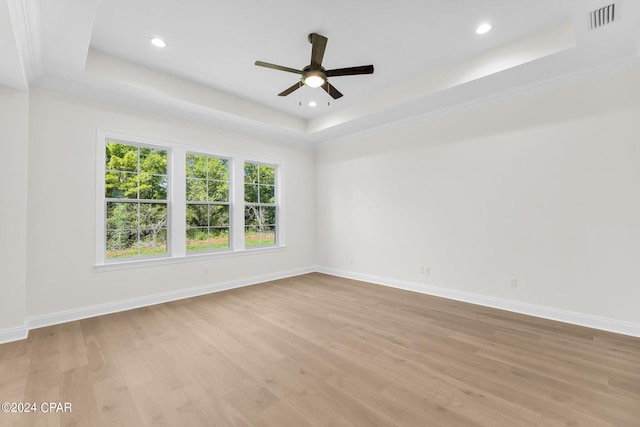 spare room with ornamental molding, a tray ceiling, ceiling fan, and light hardwood / wood-style flooring