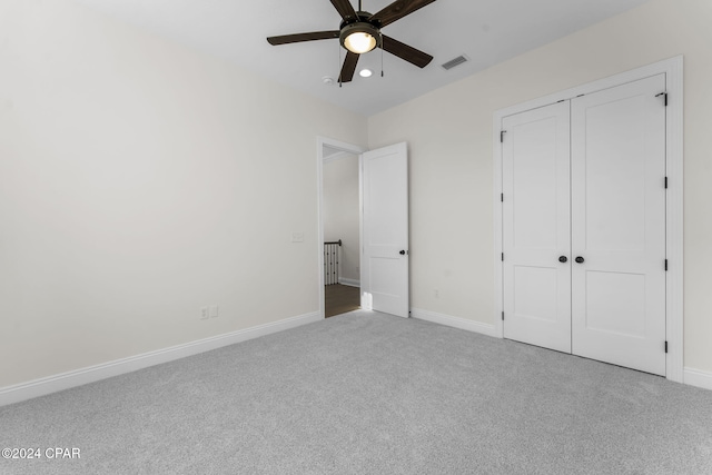 unfurnished bedroom with ceiling fan, light colored carpet, and a closet