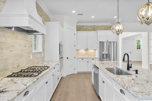 kitchen with stainless steel appliances, sink, hanging light fixtures, and premium range hood