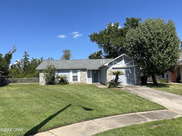 ranch-style home featuring fence, a garage, stone siding, driveway, and a front lawn