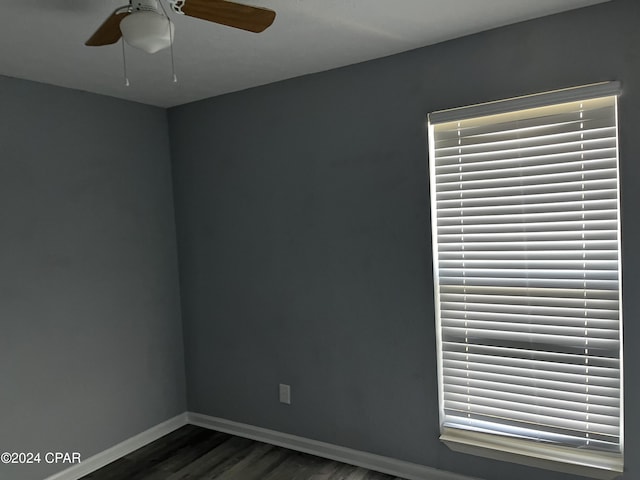 empty room featuring a ceiling fan, dark wood finished floors, and baseboards