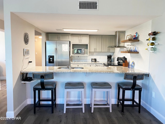 kitchen featuring stainless steel appliances, backsplash, exhaust hood, a kitchen breakfast bar, and dark wood-type flooring