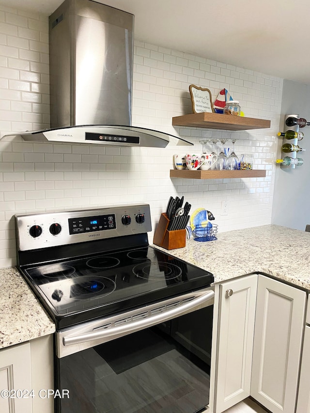 kitchen with wall chimney range hood, stainless steel range with electric cooktop, and light stone countertops