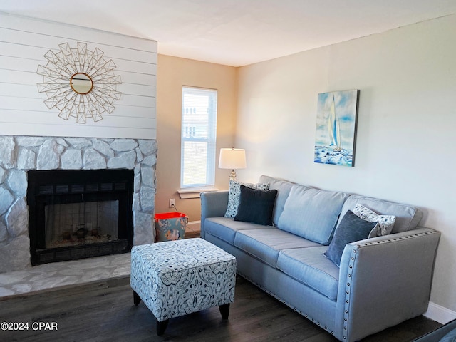 living room featuring dark wood-type flooring and a stone fireplace