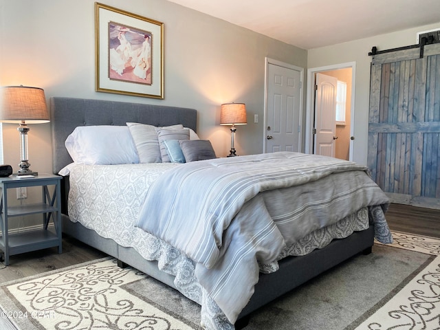 bedroom featuring a barn door and hardwood / wood-style flooring