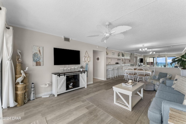 living room with a textured ceiling, light hardwood / wood-style flooring, and ceiling fan with notable chandelier