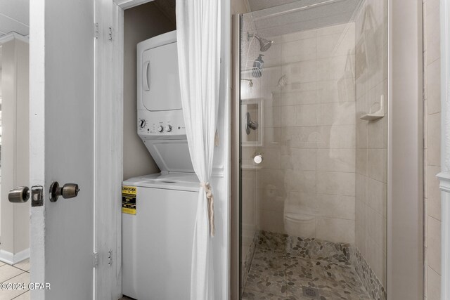 washroom featuring light tile patterned flooring and stacked washer / dryer