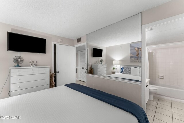 tiled bedroom with a textured ceiling, a closet, and connected bathroom