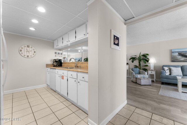 kitchen featuring sink, light wood-type flooring, white cabinets, and crown molding