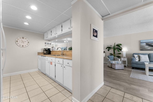 kitchen featuring light tile patterned floors, a sink, white cabinets, open floor plan, and light countertops