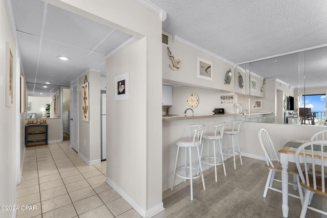 kitchen featuring crown molding, visible vents, light countertops, white cabinets, and a peninsula