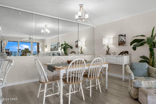 dining space with light wood-type flooring, ceiling fan with notable chandelier, and a textured ceiling