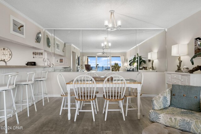 dining space with hardwood / wood-style flooring, crown molding, a notable chandelier, and a textured ceiling