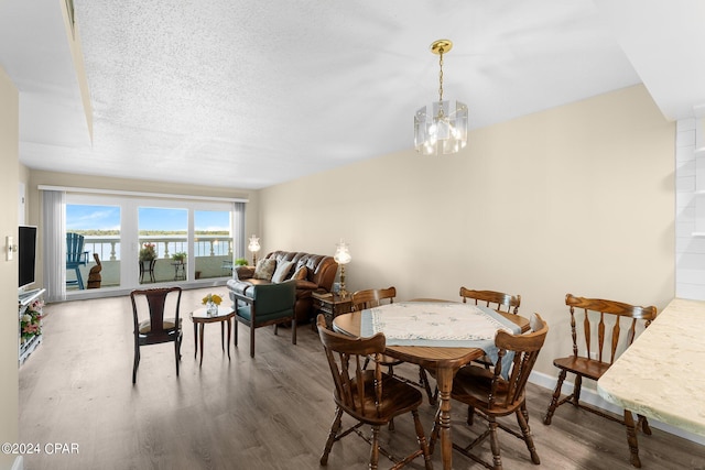 dining space with a notable chandelier, a textured ceiling, baseboards, and wood finished floors