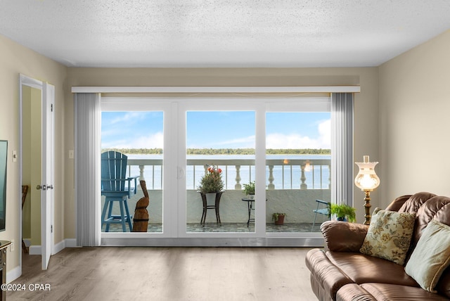 living area with a textured ceiling, a water view, and wood finished floors