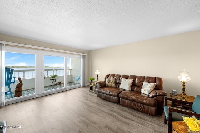 living room featuring a textured ceiling, a water view, and wood finished floors