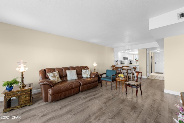 living room with light wood finished floors, visible vents, and baseboards