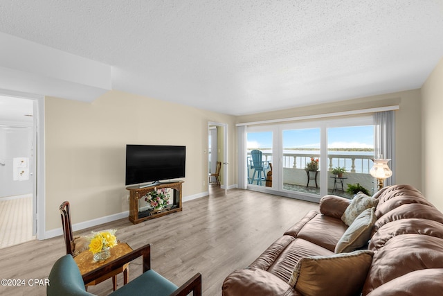 living room with baseboards, light wood-style flooring, and a textured ceiling