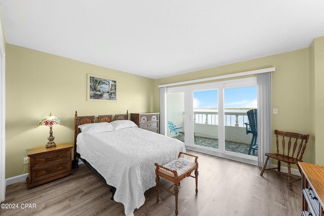 bedroom featuring access to exterior, baseboards, and wood finished floors