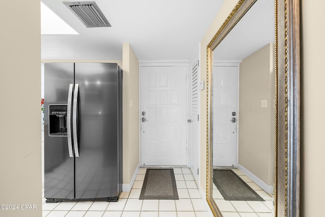 interior space featuring light tile patterned floors, stainless steel fridge, visible vents, and baseboards