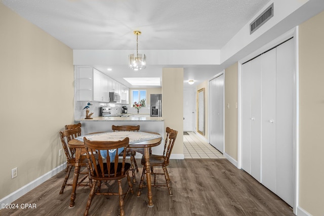 dining area with dark wood-style floors, baseboards, visible vents, and a notable chandelier