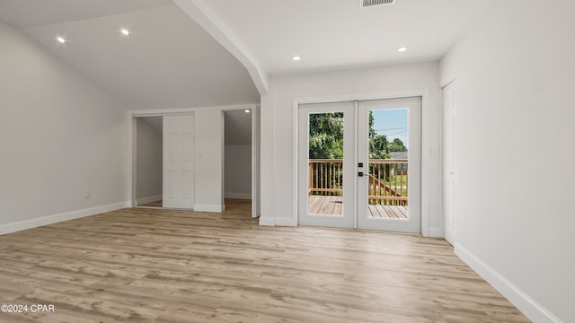 unfurnished bedroom featuring light hardwood / wood-style floors, a closet, access to exterior, lofted ceiling, and french doors