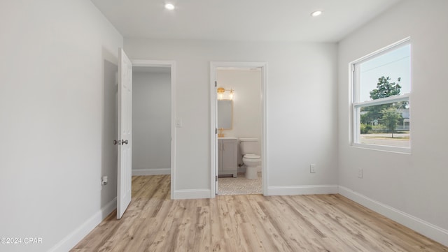 unfurnished bedroom featuring connected bathroom and light hardwood / wood-style floors