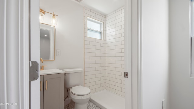 bathroom with tiled shower, vanity, and toilet