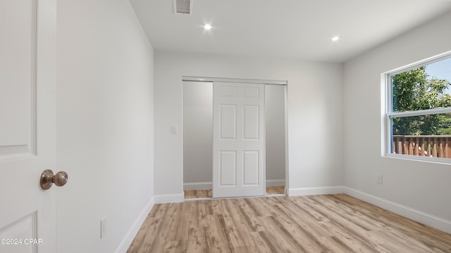 unfurnished bedroom with light hardwood / wood-style flooring and a closet