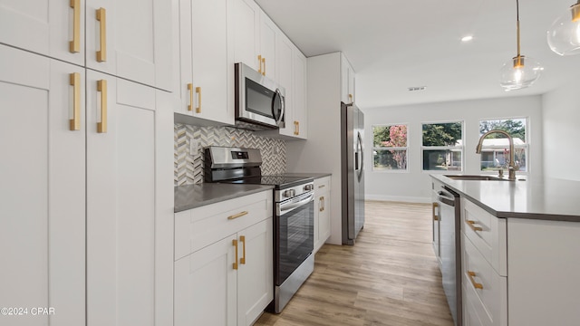 kitchen with pendant lighting, sink, light hardwood / wood-style flooring, white cabinetry, and appliances with stainless steel finishes