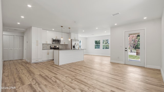 kitchen featuring pendant lighting, a kitchen island with sink, white cabinetry, light hardwood / wood-style flooring, and appliances with stainless steel finishes