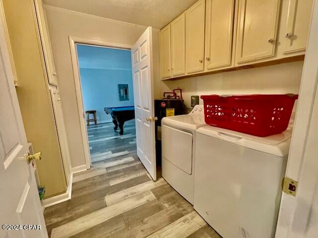 laundry room with cabinets, light wood-type flooring, pool table, a textured ceiling, and washer and clothes dryer