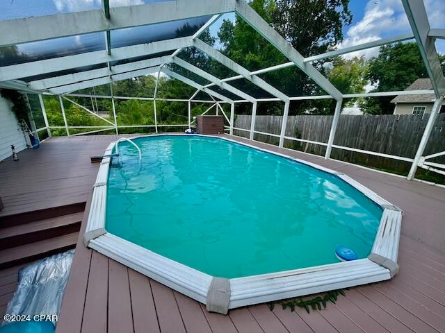 view of pool featuring a wooden deck and glass enclosure