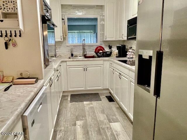 kitchen with sink, white cabinetry, light hardwood / wood-style flooring, backsplash, and black appliances