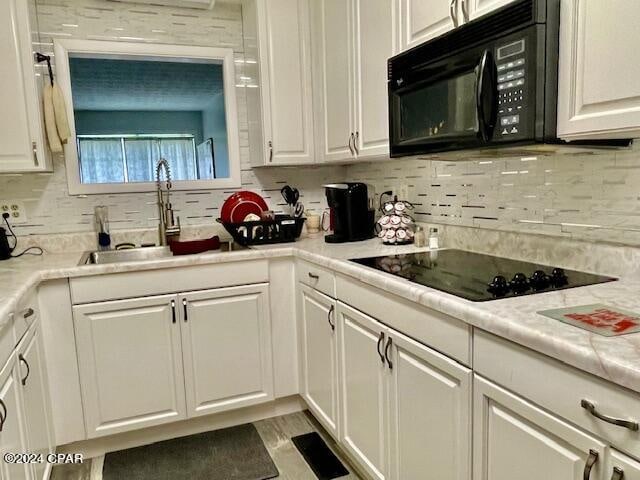 kitchen featuring sink, backsplash, white cabinetry, and black appliances