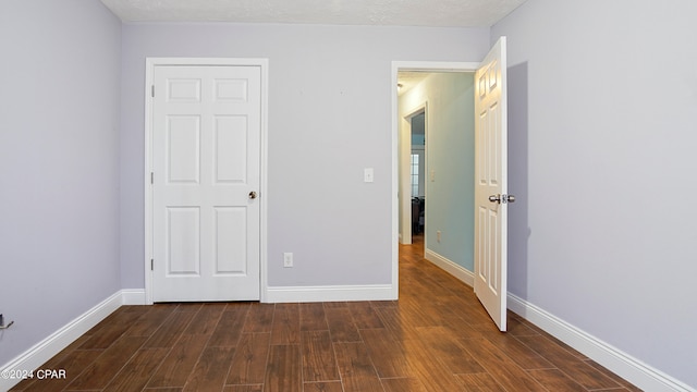 unfurnished bedroom with a textured ceiling and dark hardwood / wood-style flooring