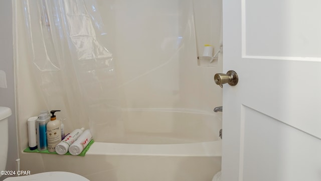 bathroom featuring shower / bathtub combination with curtain and toilet