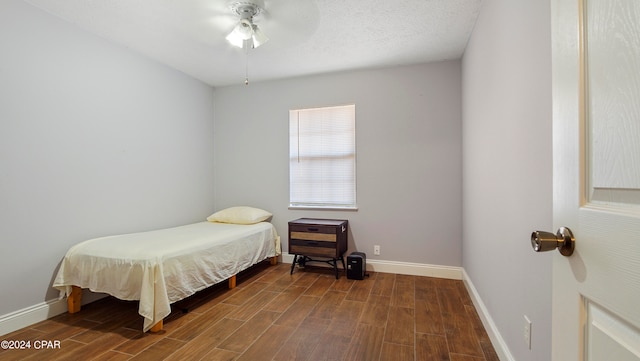 bedroom with ceiling fan, hardwood / wood-style flooring, and a textured ceiling