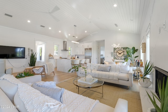 living room with high vaulted ceiling, light hardwood / wood-style floors, and ceiling fan with notable chandelier