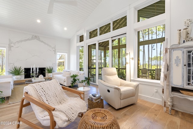 sunroom with ceiling fan, a fireplace, and lofted ceiling