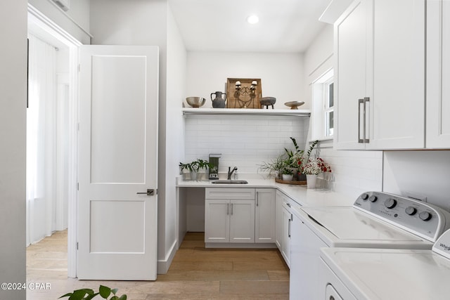 bar featuring sink, decorative backsplash, white cabinets, and light wood-type flooring