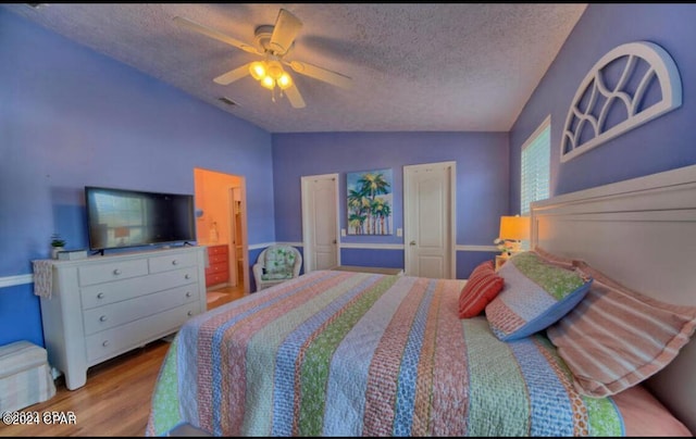 bedroom with light hardwood / wood-style flooring, ceiling fan, a textured ceiling, and vaulted ceiling