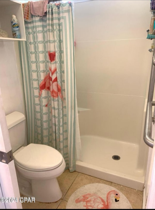 bathroom featuring toilet, a shower with curtain, and tile patterned floors