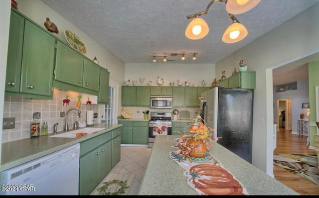 kitchen with green cabinets, light wood-type flooring, appliances with stainless steel finishes, sink, and a textured ceiling