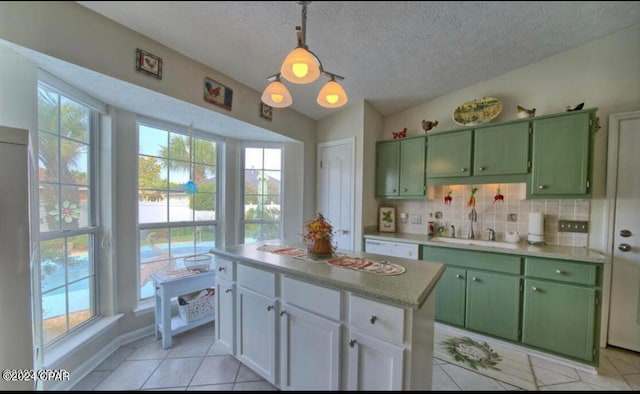 kitchen with green cabinets, a center island, decorative light fixtures, light tile patterned flooring, and a textured ceiling